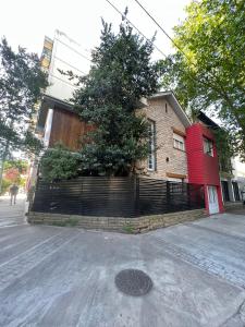 ein rotes Haus mit einem Zaun neben einer Straße in der Unterkunft Habitaciones Garay 3100 in Mar del Plata