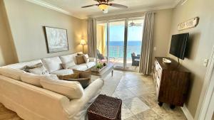 uma sala de estar com um sofá branco e uma televisão em Tropic Winds 1606 em Panama City Beach