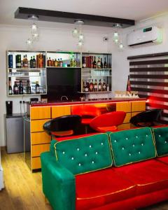 um bar com cadeiras vermelhas e verdes e um balcão em Dozubel Hotel em Abuja