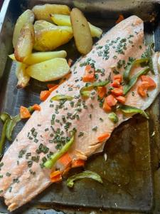 una sartén con pescado y verduras sobre una mesa en Cabaña cerca del Aeropuerto, en Puerto Montt