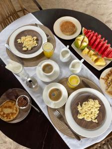 einen Tisch mit Teller mit Speisen und Tassen Kaffee in der Unterkunft Kuwa Zanzibar in Kiwengwa