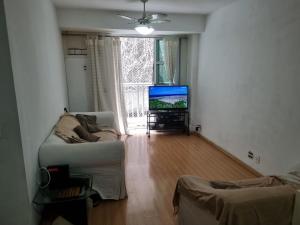 uma sala de estar com um sofá e uma televisão em Santa Clara Residence bedrooms no Rio de Janeiro
