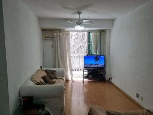 uma sala de estar com um sofá e uma televisão em Santa Clara Residence bedrooms no Rio de Janeiro