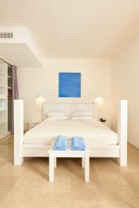 uma cama branca com duas almofadas azuis em Meditur Puglia by Itafirst Hotels em Specchiolla