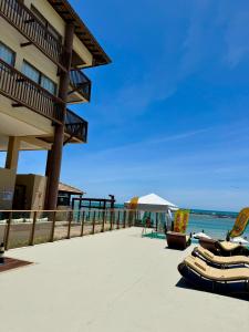 - une plage avec des chaises, un bâtiment et l'océan dans l'établissement Apartamento em Barra Bali, Resort de Luxo, Barra de São de Miguel - 223, à Barra de São Miguel