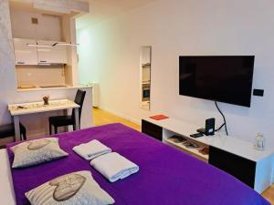 Habitación con cama morada, mesa y TV. en Nova galerija Ema, en Zagreb