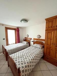 1 dormitorio con 2 camas y armario de madera en Livigno Elisir Petit, en Livigno