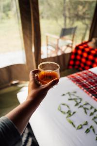 una persona sosteniendo una bebida en un vaso en Olimba Mara Camp en Mara Simba