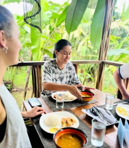 een vrouw die aan een tafel zit eten bij Ecohotel Riomar Mecana in Bahía Solano