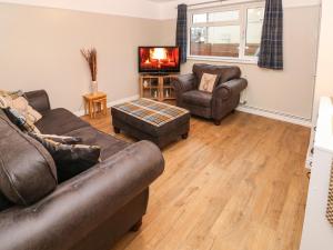 uma sala de estar com dois sofás e uma televisão em Sŵn Y Môr em Burry Port
