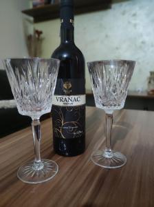 a bottle of wine and two wine glasses on a table at Stan na dan Pale Apartman Danica in Pale