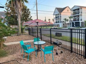 a table with chairs and an umbrella next to a fence at Nautical Retreat (Unit 5) in Galveston