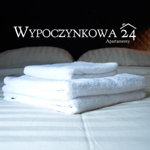 a pile of white towels sitting on a bed at Apartamenty Wypoczynkowa 24 - 700m od Park Wodny Suntago Wręcza in Krzyżówka