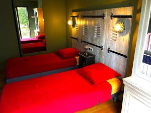 1 Schlafzimmer mit 2 roten Betten und einem Spiegel in der Unterkunft Coté Notre Dame des Marins Appartement T3 (80 m2) avec Grande Terrasse in Martigues