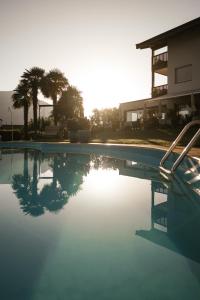 un bassin d'eau avec des palmiers en arrière-plan dans l'établissement Boutiquehotel Minigolf, à Tirolo