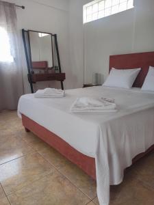 1 cama con sábanas blancas y espejo en una habitación en Maisonette Kavousi with Mountain and Village View, en Kavoúsion