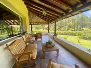 une terrasse couverte avec des chaises et des tables ainsi qu'une grande fenêtre dans l'établissement Posada Sausalito, à Santa Rosa de Calamuchita