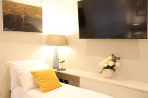 een kamer met een bed met een geel kussen en een televisie bij Meyland suites centro in Milaan