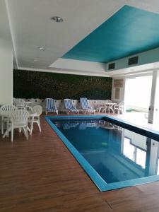 a swimming pool with white chairs and a table and chairs at Sierra Huasteca Inn in Ciudad Valles