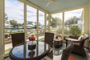 un porche cubierto con mesa de cristal y sillas en Montage Palmetto Bluff, en Bluffton