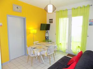 une salle à manger avec une table et un mur jaune dans l'établissement Vaux sur Mer - Quartier PONTAILLAC - APPARTEMENT - PISCINE COLLECTIVE, à Vaux-sur-Mer