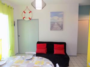sala de estar con sofá negro y almohadas rojas en Vaux sur Mer - Quartier PONTAILLAC - APPARTEMENT - PISCINE COLLECTIVE, en Vaux-sur-Mer