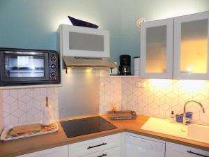 una pequeña cocina con microondas y fregadero en Vaux sur Mer - Quartier PONTAILLAC - APPARTEMENT - PISCINE COLLECTIVE, en Vaux-sur-Mer