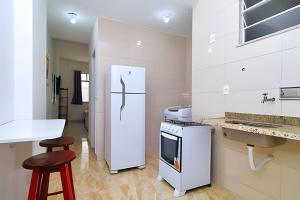 a white kitchen with a refrigerator and a counter at Studio na quadra da praia, estação de metro 5min andando, mercados e comércios próximos in Rio de Janeiro