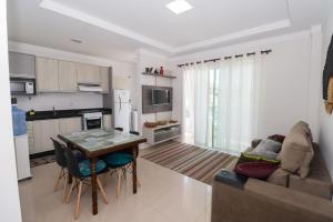 a kitchen and living room with a table and a couch at 377 - Belissimo apartamento na praia de Bombas in Bombinhas