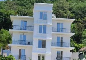 um edifício branco com janelas e árvores azuis em Hotel Fama em Durrës