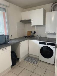 a kitchen with white cabinets and a black dishwasher at Le Central-Proche Gare et Genève in Annemasse