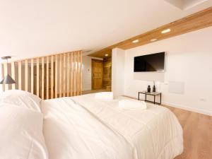 una camera bianca con un grande letto e una TV a schermo piatto di Wolf House BnB a Coppito