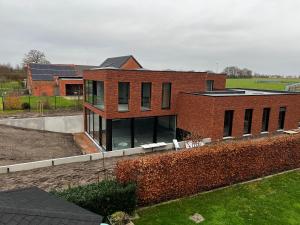 une maison en briques rouges avec une clôture devant elle dans l'établissement Vakantievilla Eetseveld, à Brée