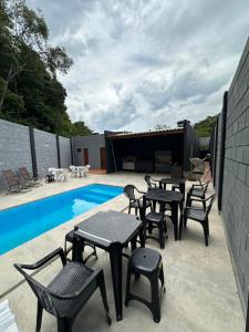 ジャカレイーにあるReserva Athenas - Clube de campoのスイミングプールの隣にテーブルと椅子付きのパティオ