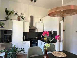 a kitchen with white cabinets and a table with pink flowers at Vondelpark Luxury Apartment in Amsterdam