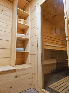 a wooden sauna with a glass door and shelves at Cottage Golenovo in Podvelka
