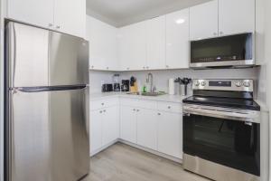 a kitchen with white cabinets and a stainless steel refrigerator at Amazing Experience in Calle Ocho in Miami