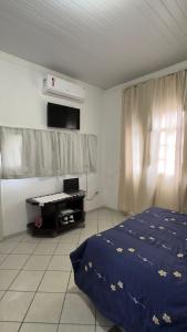 1 dormitorio con cama y escritorio. en Cantinho do SOSSEGO, a 2 km da praia de Itapuã, no centro da cidade, wifi, ideal para CASAL en Vila Velha