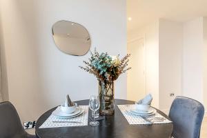 a dining room table with a vase of flowers and a mirror at Chic and Sleek Oasis in London