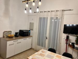une cuisine avec une table, un four micro-ondes et une télévision dans l'établissement Maison saint cyprien plage, à Saint-Cyprien