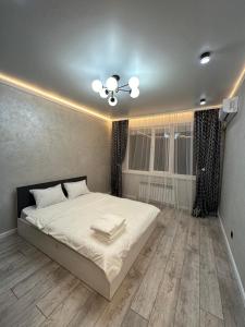 a bedroom with a large bed with white sheets at Аэропорт Алтын сити in Almaty