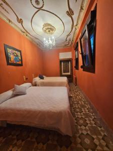 Cette chambre comprend 3 lits avec des murs orange et un lustre. dans l'établissement Fabrica de Sueños, à Gandía