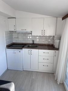 a kitchen with white cabinets and a sink at Tepe Hotel in Alaçatı