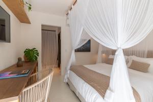 Schlafzimmer mit einem Bett mit weißen Vorhängen in der Unterkunft Hotel Boutique Vila São João in Trancoso