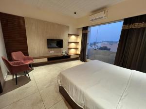 a hotel room with a bed and a chair and a television at HOTEL ANANTA in Ambāla