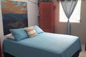 1 dormitorio con cama con sábanas azules y ventana en Casa Pico Bonito, en El Porvenir