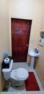 uma casa de banho com um WC, um lavatório e uma porta vermelha em Casa Pico Bonito em El Porvenir