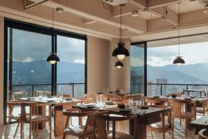 a restaurant with wooden tables and chairs and large windows at Kiin Living - Adults Only in Medellín