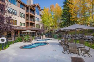 海狸溪的住宿－96 Highlands Slopeside #502, Beaver Creek，一个带桌椅的庭院和一个游泳池