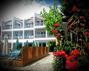 a large white building with red flowers in front of it at Aggelos Apartments & Deluxe Studios in Nydri